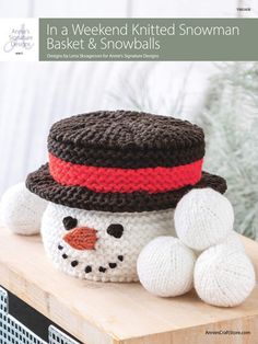 a knitted snowman sitting on top of a wooden table