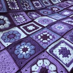 a purple and white crocheted blanket on top of a bed