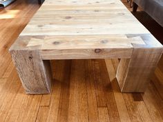 a wooden table sitting on top of a hard wood floor next to a couch in a living room