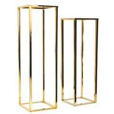 two tall gold metal vases sitting next to each other on a white background,