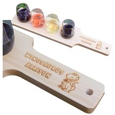 a wooden bottle opener with four different colored liquids in it and the word, dinosaurs allson