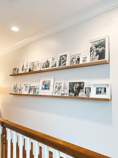 several wooden shelves with pictures on them above a bannister in a home's entryway