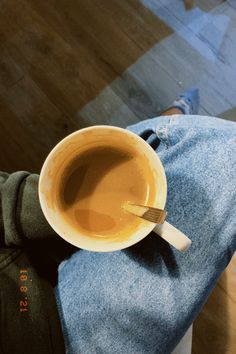 a cup of coffee is sitting on someone's lap with a spoon in it