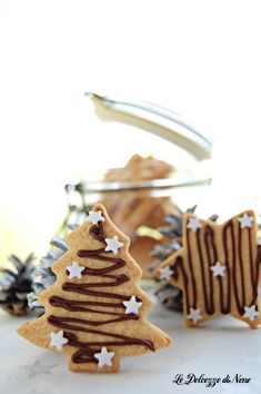 cookies decorated like christmas trees with chocolate drizzle on them and pine cones in the background