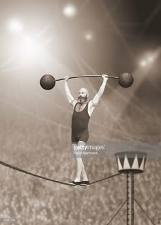 a woman balances on a tightrope while holding two balls above her head