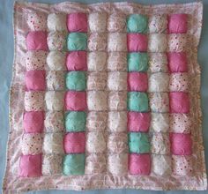 a pink and blue quilted blanket with baby's blankets on top of it