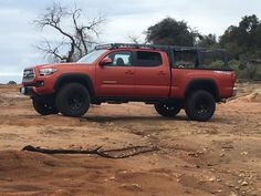 a red truck parked on top of a dirt field