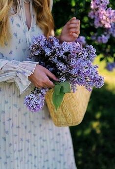 a woman holding a basket full of purple flowers