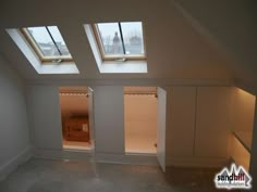 an empty room with two windows and some cupboards