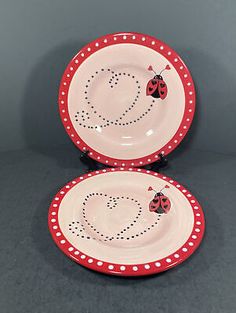 two red and white plates with ladybugs painted on the sides, one is empty