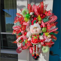 a christmas wreath hanging on the front door with santa's helper and candy canes