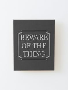 a square black and white sign with the words beware of the thing on it