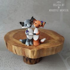 two small figurines sitting on top of a wooden table