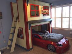 a child's bedroom with a loft bed and a red car under the stairs