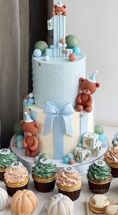 a baby shower cake with cupcakes and teddy bears on it's side