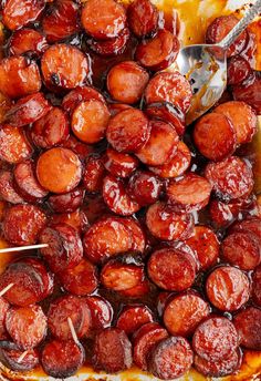 a pan filled with cooked sausages and skewered toothpicks in sauce