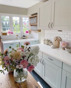 a vase filled with lots of flowers on top of a wooden table in a kitchen