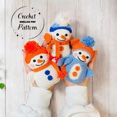 three crocheted snowmen holding hands in front of a white wooden background with text that reads, crochet english pop pattern