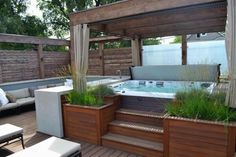 a hot tub sitting on top of a wooden deck next to a covered patio area