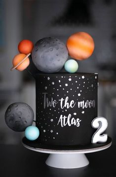 a black cake with planets on it and the words two the moon atlas written in white