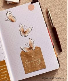 an open notebook with some butterflies on it and a pen next to the page that says january