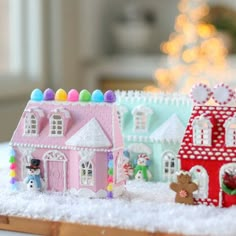 two small houses are sitting in the snow with a christmas tree in the back ground