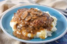 a blue plate topped with mashed potatoes covered in gravy