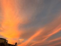 the sky is filled with colorful clouds as the sun sets in the distance behind some buildings