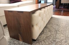 a white couch sitting next to a wooden table on top of a carpeted floor