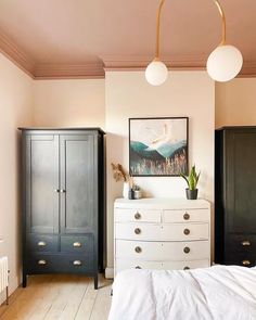 a bedroom with two black and white dressers next to a painting on the wall