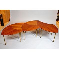 a set of three tables made out of wood and metal legs with curved top, on white background