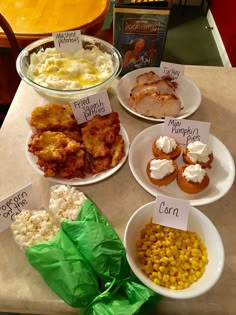 several plates with different foods on them sitting on a table next to a box of popcorn