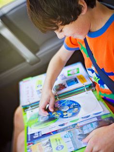 a young boy sitting in the back seat of a car holding onto a cd and looking at it