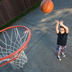 a young boy throwing a basketball up into the air