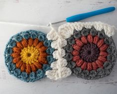 two crocheted coasters sitting next to each other on a white surface with a blue handled crochet hook