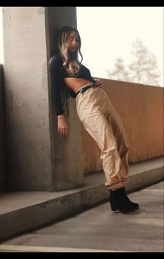 a woman leaning against a wall with her legs crossed