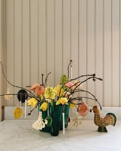 a vase filled with flowers sitting on top of a table next to a chicken figurine