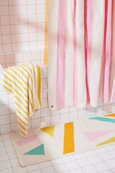 a bathroom with pink, yellow and white rugs on the floor next to a shower curtain