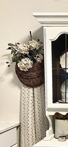 a white china cabinet with flowers in it