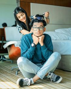 a man sitting on the floor next to a woman who is combing her hair