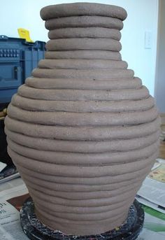 a large brown vase sitting on top of a table next to a pile of papers