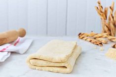 some bread is sitting on a table next to rolling pins and other food items that are laying around