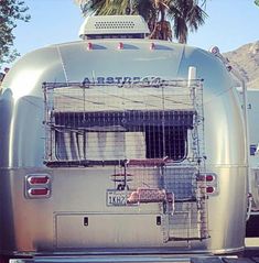 an airstream is parked on the side of the road in front of palm trees