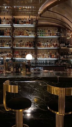 a bar with two stools in front of it and shelves full of liquor bottles