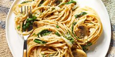 a white plate topped with pasta covered in sauce and spinach next to a fork