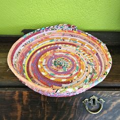 a decorative basket sitting on top of a wooden table next to a metal door knocker