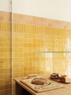 a loaf of bread sitting on top of a wooden table in front of a yellow tiled wall