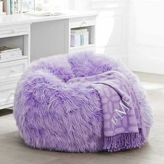 a purple bean bag chair sitting on top of a hard wood floor next to a white desk