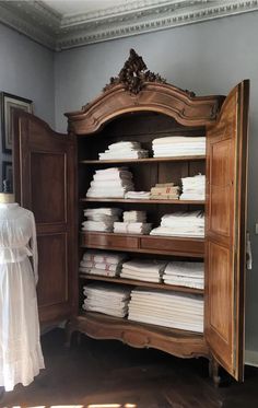 an old wooden cabinet filled with lots of white sheets