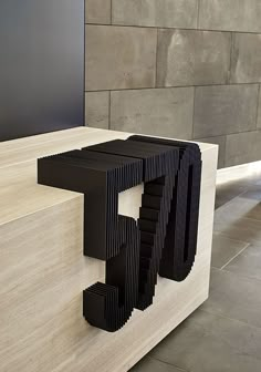 a black sculpture sitting on top of a wooden table next to a wall and floor